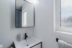 White vanity with a rectangular sink, matte black faucet, and a rectangular mirror with a black frame - 