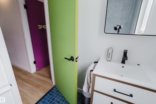 White vanity with built-in sink, matte black faucet, and rectangular mirror - 9059 52 Street Nw, Edmonton, AB - Indoor