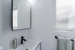 Wall-mounted rectangular mirror with a black frame, matte black faucet, integrated sink, and privacy glass window - 