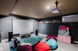 Media room featuring a drop ceiling with recessed lighting, a mounted projector, and a pull-down screen - 