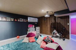 Recessed lighting, wood-panel accent wall, projector with ceiling mount, and drop ceiling with integrated lighting - 