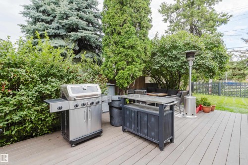 Expansive outdoor deck with composite decking, surrounded by mature trees and shrubs, featuring a built-in outdoor bar - 9059 52 Street Nw, Edmonton, AB - Outdoor With Deck Patio Veranda With Exterior