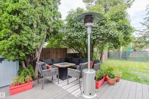 Composite decking with a built-in privacy wall, surrounded by mature trees and a manicured lawn - 9059 52 Street Nw, Edmonton, AB - Outdoor With Deck Patio Veranda