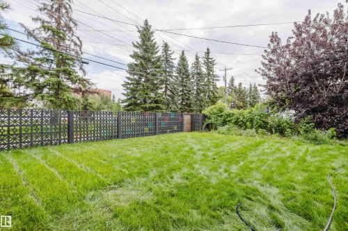 Expansive green space featuring a decorative privacy fence and mature trees - 9059 52 Street Nw, Edmonton, AB - Outdoor