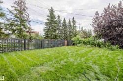Expansive green space featuring a decorative privacy fence and mature trees - 