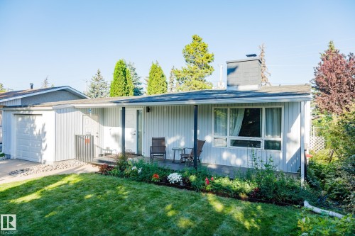 Modern single-story residence featuring corrugated metal siding, a covered front porch with large windows, and an attached garage - 9059 52 Street Nw, Edmonton, AB - Outdoor With Deck Patio Veranda