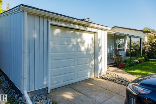Attached garage with panel door, concrete driveway, and front porch with overhead awning - 9059 52 Street Nw, Edmonton, AB - Outdoor With Exterior