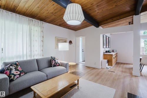 Exposed wood-beam vaulted ceiling, wood-finish flooring, built-in cabinetry, and ample natural light - 9059 52 Street Nw, Edmonton, AB - Indoor Photo Showing Living Room