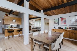 Vaulted wood-paneled ceilings with exposed beams, wood-finish flooring, and a dining area with built-in cabinetry featuring white countertops - 