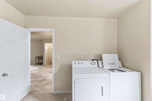 Dedicated laundry area with durable carpet flooring, neutral wall paint, and white trim - 12243 104 Street Nw, Edmonton, AB - Indoor Photo Showing Laundry Room