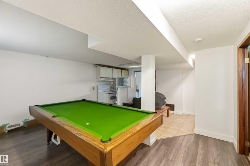 Recreation room featuring wood-finish flooring and a partial kitchen with white cabinetry - 12243 104 Street Nw, Edmonton, AB - Indoor Photo Showing Other Room