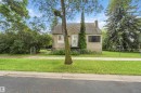 Cottage-style residence featuring a stucco exterior, front porch with railing, sloped roofline, and a prominent chimney - 12243 104 Street Nw, Edmonton, AB  - Outdoor 