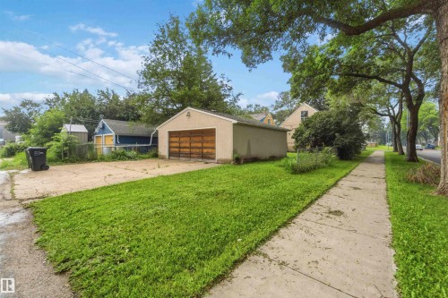 Detached garage with a wood-finish overhead door, concrete driveway, and a front lawn - 12243 104 Street Nw, Edmonton, AB - Outdoor