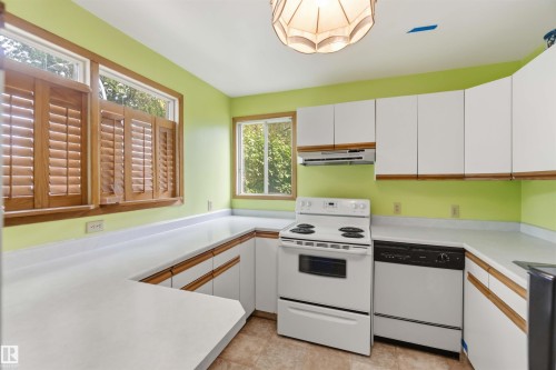 U-shaped kitchen featuring white cabinetry with wood trim, white countertops, an electric range, and a dishwasher - 12243 104 Street Nw, Edmonton, AB - Indoor Photo Showing Kitchen