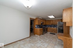 Kitchen featuring wood cabinetry, tile flooring, stainless steel appliances, and a blue tile backsplash - 