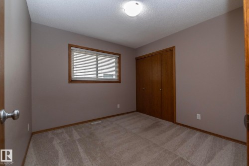 Wall-to-wall carpeting, wood-finish bi-fold closet doors, and a window with blinds - 11138 30 Avenue Nw, Edmonton, AB - Indoor Photo Showing Other Room