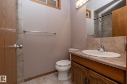 Vanity with integrated sink, wood-finish cabinetry, neutral countertop, and tiled flooring - 