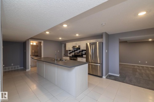 Recessed lighting illuminates the kitchen featuring a large center island with dual sinks, stainless steel appliances, and white cabinetry - 11138 30 Avenue Nw, Edmonton, AB - Indoor Photo Showing Kitchen With Stainless Steel Kitchen With Double Sink