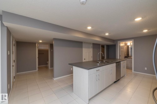 Central island with integrated sink and dishwasher, white tile flooring, recessed lighting, and a neutral wall color palette - 11138 30 Avenue Nw, Edmonton, AB - Indoor Photo Showing Kitchen With Double Sink