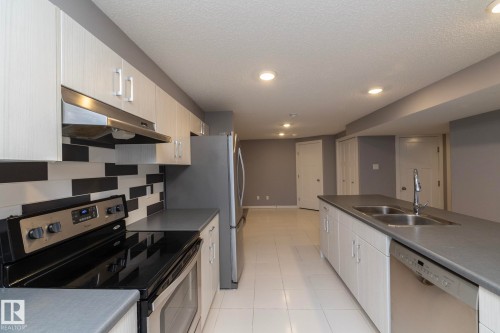 Modern kitchen featuring a dual-basin stainless steel sink, integrated dishwasher, and a black and white tiled backsplash - 11138 30 Avenue Nw, Edmonton, AB - Indoor Photo Showing Kitchen With Stainless Steel Kitchen With Double Sink
