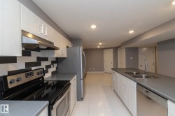 Modern kitchen featuring a dual-basin stainless steel sink, integrated dishwasher, and a black and white tiled backsplash - 
