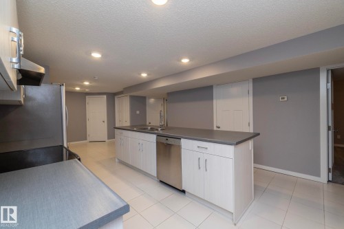 Kitchen island with integrated sink, stainless steel dishwasher, light wood-finish cabinetry, and recessed lighting - 11138 30 Avenue Nw, Edmonton, AB - Indoor Photo Showing Kitchen