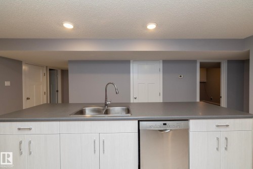 Kitchen island with dual basin stainless steel sink, gooseneck faucet, and integrated dishwasher - 11138 30 Avenue Nw, Edmonton, AB - Indoor Photo Showing Kitchen With Double Sink