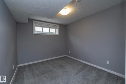 Neutral-toned walls with a white trim, patterned carpet flooring, and a single window with blinds - 11138 30 Avenue Nw, Edmonton, AB - Indoor Photo Showing Other Room