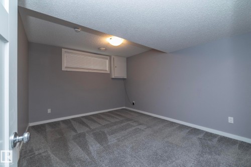 Recessed window with white blinds, wall-mounted light fixture, and gray patterned carpet - 11138 30 Avenue Nw, Edmonton, AB - Indoor Photo Showing Other Room