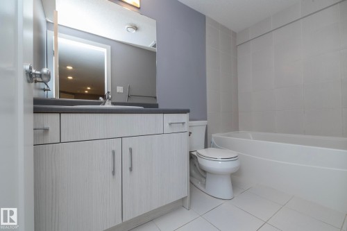 Modern vanity with integrated sink, dark countertop, and brushed nickel hardware - 11138 30 Avenue Nw, Edmonton, AB - Indoor Photo Showing Bathroom
