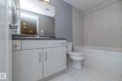 Modern vanity with integrated sink, dark countertop, and brushed nickel hardware - 