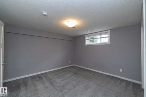 Gray carpeted flooring, window with white trim, wall-mounted light fixture, white interior door, and gray wall paint - 11138 30 Avenue Nw, Edmonton, AB - Indoor Photo Showing Other Room