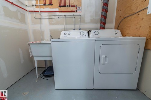 White laundry appliances, including a washing machine and dryer, are paired with a utility sink - 11138 30 Avenue Nw, Edmonton, AB - Indoor Photo Showing Laundry Room