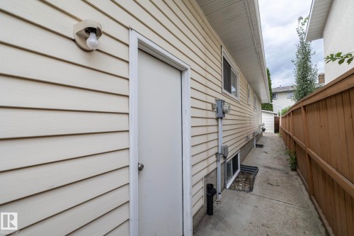 Siding exterior with multiple windows, a rear entry door, and concrete walkway - 11138 30 Avenue Nw, Edmonton, AB - Outdoor With Exterior