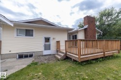 Exterior featuring wood siding, a red brick chimney, and a raised wood deck with railing - 