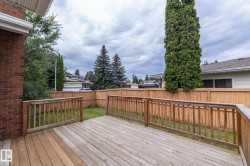 Expansive wood deck with wood railings, featuring a brick exterior wall and a wood privacy fence - 