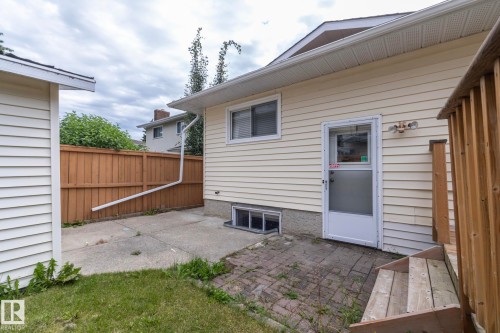 Siding exterior with a white storm door, wood deck stairs, and a partial wood fence - 11138 30 Avenue Nw, Edmonton, AB - Outdoor With Exterior