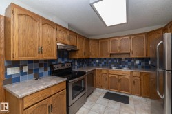 Kitchen featuring wood cabinetry, stainless steel appliances, patterned tile backsplash, and light-toned countertops - 