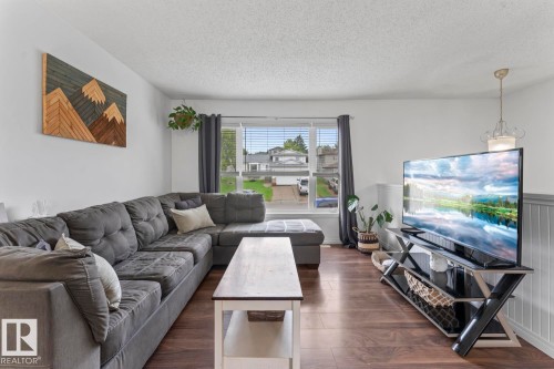 Wood-finish flooring throughout, bright white walls, and a large window with blinds - 5330 43 Street, Cold Lake, AB - Indoor Photo Showing Living Room