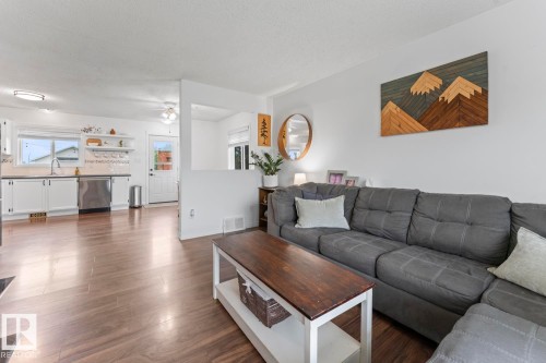 Wood-finish flooring throughout, white cabinetry, stainless steel dishwasher, and a double basin sink - 5330 43 Street, Cold Lake, AB - Indoor Photo Showing Living Room