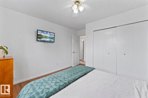 White walls, wood-finish flooring, ceiling-mounted light fixture, and bi-fold closet doors - 5330 43 Street, Cold Lake, AB - Indoor Photo Showing Bedroom