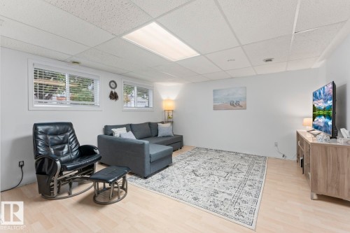Recessed windows with blinds, drop ceiling with integrated lighting, light wood-finish flooring, and white walls - 5330 43 Street, Cold Lake, AB - Indoor