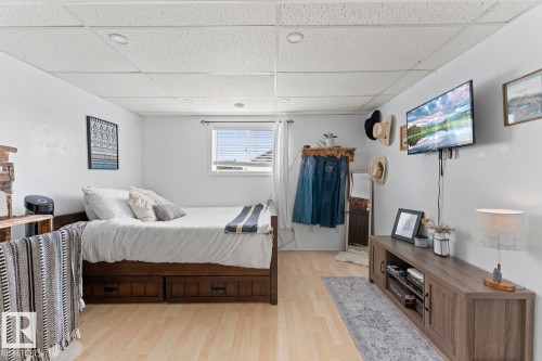 Recessed lighting, wood-finish flooring, a window with blinds, and a wall-mounted television - 5330 43 Street, Cold Lake, AB - Indoor Photo Showing Bedroom