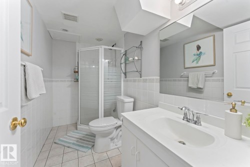 White subway tile wainscoting, walk-in shower with frosted glass enclosure, single vanity with integrated sink, chrome faucet, and large wall-mounted mirror - 5330 43 Street, Cold Lake, AB - Indoor Photo Showing Bathroom