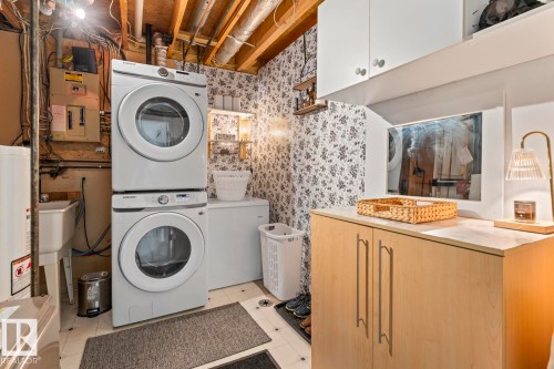 Stacked washer and dryer, laundry sink, built-in cabinetry, and overhead storage - 5330 43 Street, Cold Lake, AB - Indoor Photo Showing Laundry Room