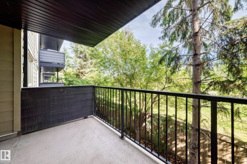 Balcony with a concrete floor, black metal railing, and a dark wood-finish privacy wall - #216 17003 67 Av Nw, Edmonton, AB - Outdoor With Balcony With Exterior
