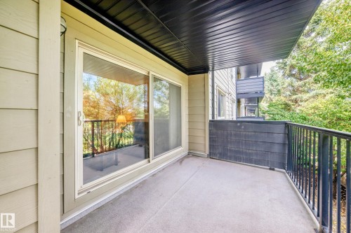 Private balcony with a concrete floor, black metal railings, and a sliding glass door entry - #216 17003 67 Av Nw, Edmonton, AB - Outdoor With Balcony With Exterior