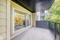 Private balcony with a concrete floor, black metal railings, and a sliding glass door entry - 