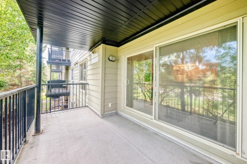 Covered balcony with concrete flooring, black metal railings, and an exterior wall featuring horizontal siding - #216 17003 67 Av Nw, Edmonton, AB - Outdoor With Balcony With Exterior