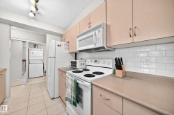 Functional kitchen featuring a full suite of white appliances, light wood-finish cabinetry, and a white subway tile backsplash - 